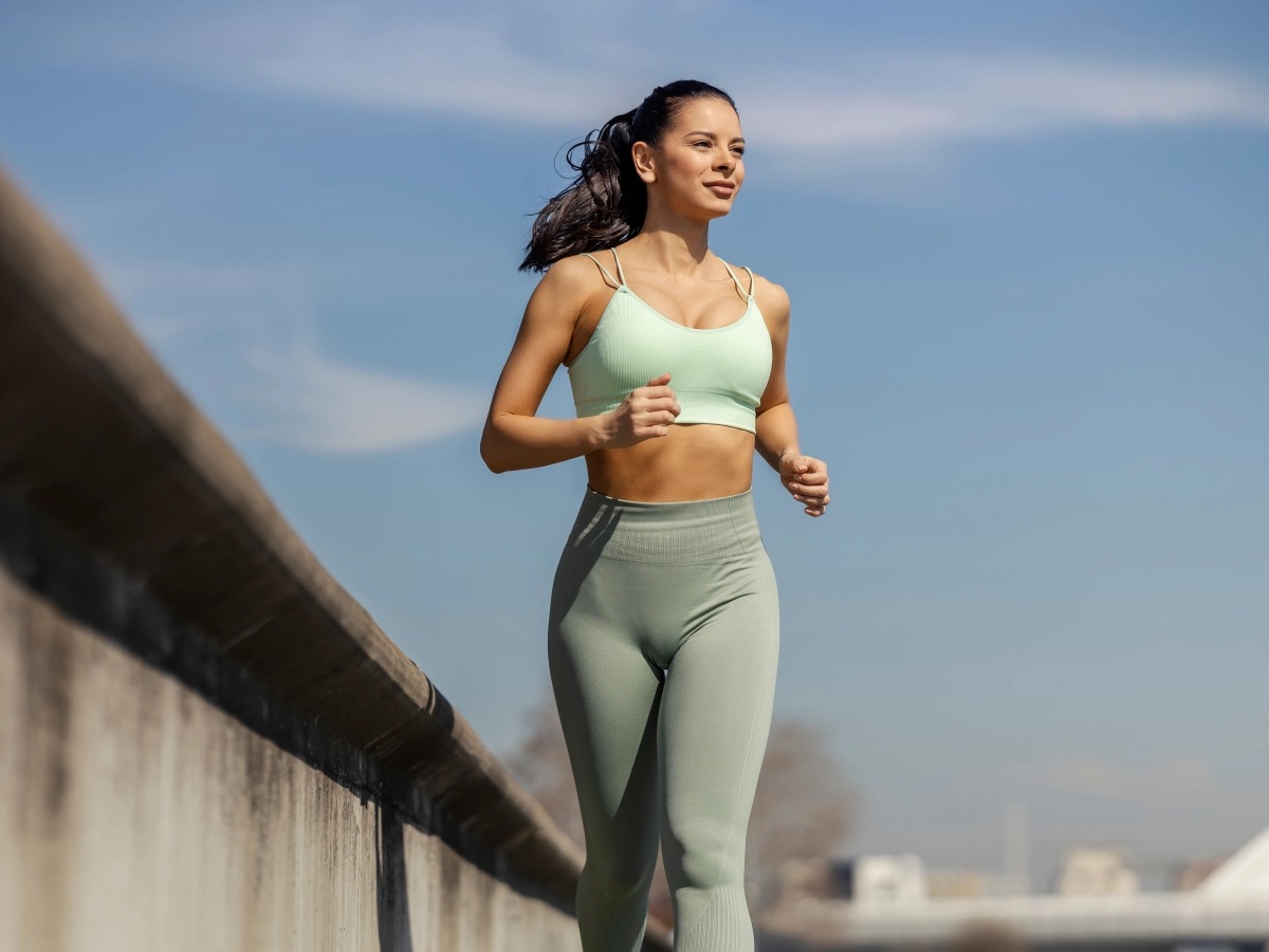 A runner on a city path, mid-stride under a clear sky