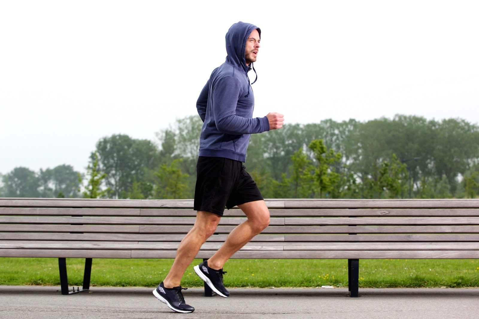 A man on an ordinary weekday run along a park path on an overcast morning